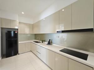 a kitchen with white cabinets and a black refrigerator at Paradigm Residence by Antlerzone in Johor Bahru