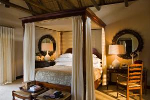 クランウィリアムにあるBushmans Kloof Wilderness Reserve and Wellness Retreatのベッドルーム(鏡付きの天蓋付きベッド付)
