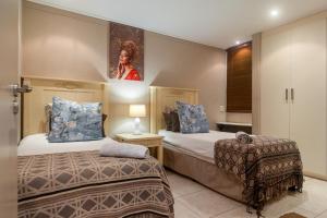 a bedroom with two beds and a painting on the wall at Elegant Family Retreat with Ocean Views in Umdloti +28 photos