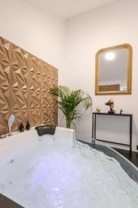 bañera en una habitación con espejo en LoveRoom avec balnéo privative, en Flémalle-Grande