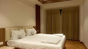 une chambre avec un lit avec des draps blancs et une fenêtre dans l'établissement Hotel Vintage Classic, à Coimbatore