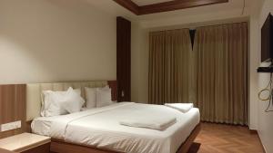une chambre avec un lit avec des draps blancs et des oreillers dans l'établissement Hotel Vintage Classic, à Coimbatore 9 autres photos