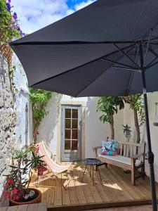 Una sombrilla negra en una terraza de madera con un banco. en Maison typique intra-muros, en Aigues-Mortes