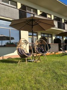two chairs and an umbrella in the grass at KAMERALNY przy promenadzie - domki, apartamenty, pokoje in Charzykowy +59 photos