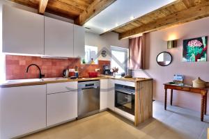 a kitchen with white cabinets and a sink at LocaLise - M6B - Ty pompon, - Maison de vacances dans le centre du Guilvinec - extérieur clos - wifi inclus - animaux bienvenus - à deux pas des plages et du port du Guilvinec in Le Guilvinec