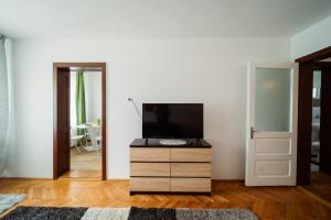 a living room with a tv on a dresser and a door at Akác Apartmanház in Odorheiu Secuiesc