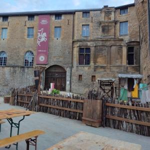 an old brick building with a wooden fence and tables at Au nid carolo in Charleville-Mézières