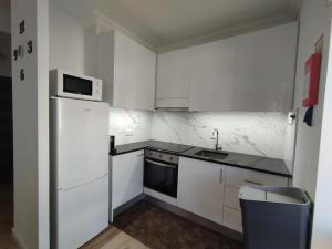 a white kitchen with a refrigerator and a microwave at Casa da TITA in Vila Praia de Âncora