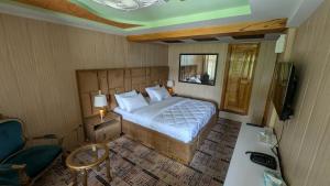 Karimabad HunzaにあるThe Jade Palace, Hunzaのベッドと椅子とテレビのある寝室