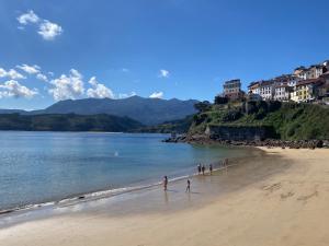 eine Gruppe von Menschen, die am Strand spazieren gehen in der Unterkunft Olas y flores silvestres 1 in Castiello de Abajo