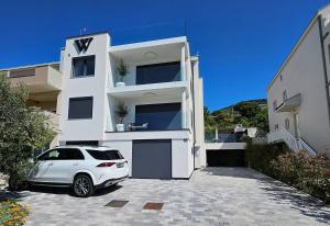 a white car parked in front of a white building at Stylish Unit in Komarna - Idyllic Retreat in Komarna +2 photos