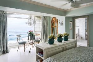 a bedroom with a bed and a table with a view of the ocean at The Oyster Box in Durban +172 photos