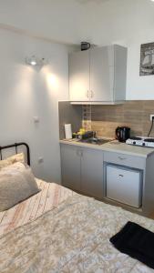 a kitchen with white cabinets and a bed in a room at Konstantinos Apartments in Kholargós