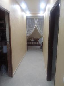 a hallway leading to a bedroom with a bed in the background at Appartement aissa in Oulad Akkou