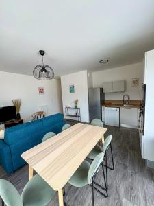 a living room with a table and a blue couch at Nid Urbain - 3 Ch et Terrasse in Saint-Herblain