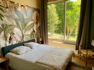 Un dormitorio con una cama y una ventana grande. en Villa Ongizatea au calme avec piscine et vue montagne, en Urrugne