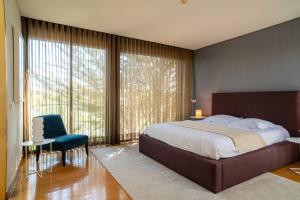 a bedroom with a large bed and a blue chair at Designer Villa in Comporta in Troia +57 photos