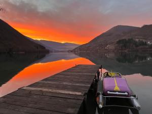 a boat tied to a dock on a lake at sunset at Vikendica - Rajski Poluotok in Jajce