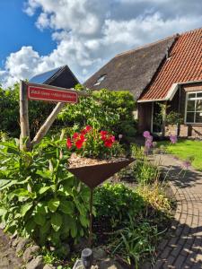 a garden with a sign in front of a house at Tinyhouse met Hot Tub en ruime privé tuin in Gees