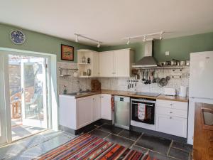 eine Küche mit weißen Schränken und einem Kühlschrank in der Unterkunft Dragon Cottage in Axminster