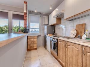 a kitchen with wooden cabinets and a large window at Platinium Wrzeszcz - Batorego in Gdańsk +5 photos
