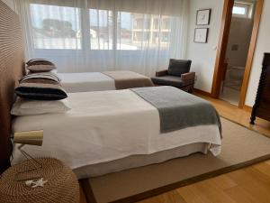 a hotel room with two beds and a chair at Moradia exclusiva junto ao mar in Gafanha da Nazaré +21 photos
