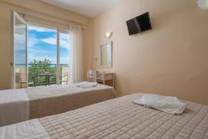a hotel room with two beds and a balcony at Julia Hotel in Fourka
