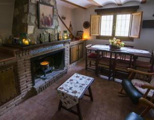 sala de estar con chimenea de piedra y mesa en El Mirador De La Malena, en Castril