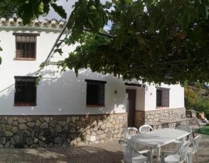 Un edificio con una mesa y sillas delante. en El Mirador De La Malena, en Castril