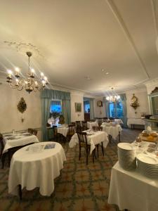 a restaurant with white tables and chairs and a chandelier at Hotel De La Paix in Interlaken
