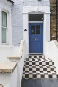 a blue door with a checkered floor in front of a house at Stylish Flat B in London