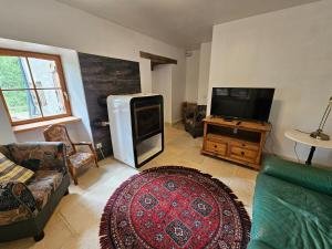 a living room with a couch and a tv at Moulin Cottage - Germaines 