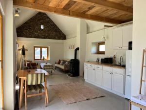 a kitchen with white cabinets and a living room at Bazalt Tigris Vendégház in Zalahaláp