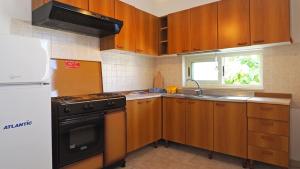 a kitchen with wooden cabinets and a stove and a sink at Appartamenti Torre Suda by Salento Affitti in Torre Suda