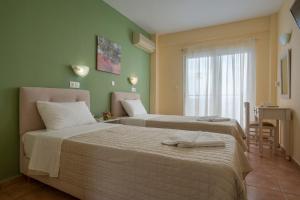 two beds in a room with green walls at Julia Hotel in Fourka