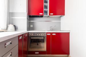 a kitchen with red cabinets and a sink at Victus Apartamenty, Patio Spa in Sopot +26 photos