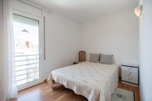 a white bedroom with a bed and a large window at Imperatore Apartment in Cunit