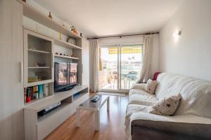 a living room with a white couch and a tv at Imperatore Apartment in Cunit