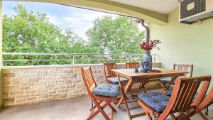 a porch with a wooden table and chairs on a balcony at Fabiola in Karigador