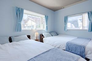 two beds in a blue room with two windows at 1200IN&OUT 10people 75m2 8bed! Exclusive house Shinjuku 13 minutes Shibuya 19 minutesIkebukuro 8 minutes Ueno 9 minutes in Tokyo