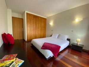 a bedroom with a large white bed with a red blanket at Tertúlias com as ondas, T2 in Vila do Conde +9 photos