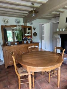 a dining room with a wooden table and chairs at petite chaumière in Tourville-sur-Pont-Audemer +3 photos