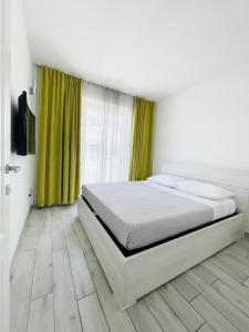 a white bedroom with a bed and green curtains at Severis Apartment Fiumicino in Fiumicino +12 photos