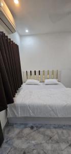 a bedroom with a large white bed with brown curtains at Shree Shiv bhakt niwas in Tuljapur