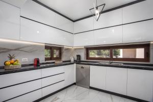 a kitchen with white cabinets and a ceiling at Oasis Luxury Villa in Rhodes Town