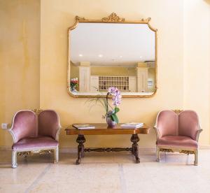2 Stühle und ein Tisch mit einem Spiegel an der Wand in der Unterkunft Hotel Spiaggia d'Oro - Charme & Boutique - Garda Lake Collection in Salò