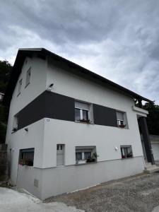 多姆扎莱Larisa apartma的白色的建筑,设有窗户和黑色的屋顶