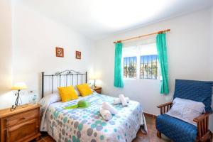 sypialnia z łóżkiem i niebieskim krzesłem w obiekcie Villa Sanchez Sol by Villa Plus w mieście Torrox