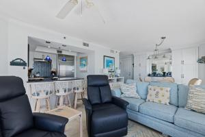 a living room with a blue couch and a kitchen at Palm House 3B with oceanfront views, pool, and private beach access in New Smyrna Beach