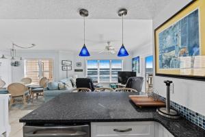 a kitchen and living room with blue pendant lights at Palm House 3B with oceanfront views, pool, and private beach access in New Smyrna Beach